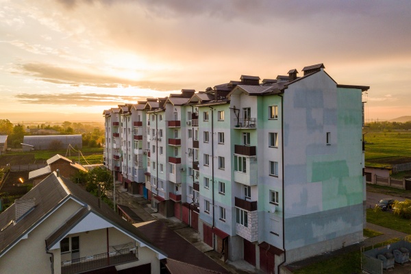 Top view of developing city landscape. Apartment building and suburb house roofs on pink sky at sunrise background. Drone photography.