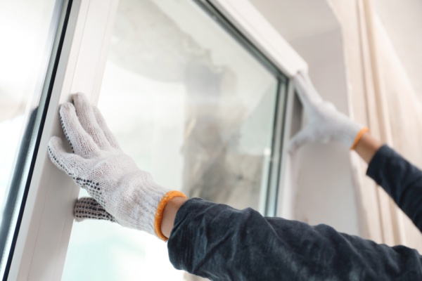 Worker installing plastic window indoors, closeup view