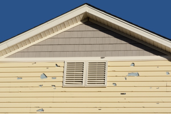 Holes in exterior siding in home from damage by hail storm