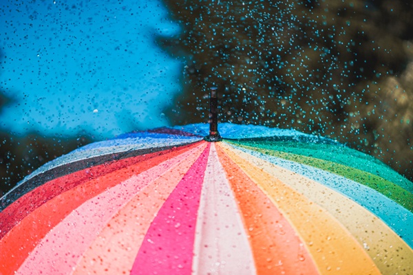 Bright colored rainbow umbrella in the rain