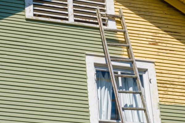 Ladder Leaning Against an Historic House with One Side Freshly Painted (Green) and the Other Side Not (Yellow)